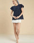 Woman wearing a navy top with lace details and a white skirt on a beige background