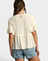 Woman wearing a cream peplum top and denim shorts on a white background