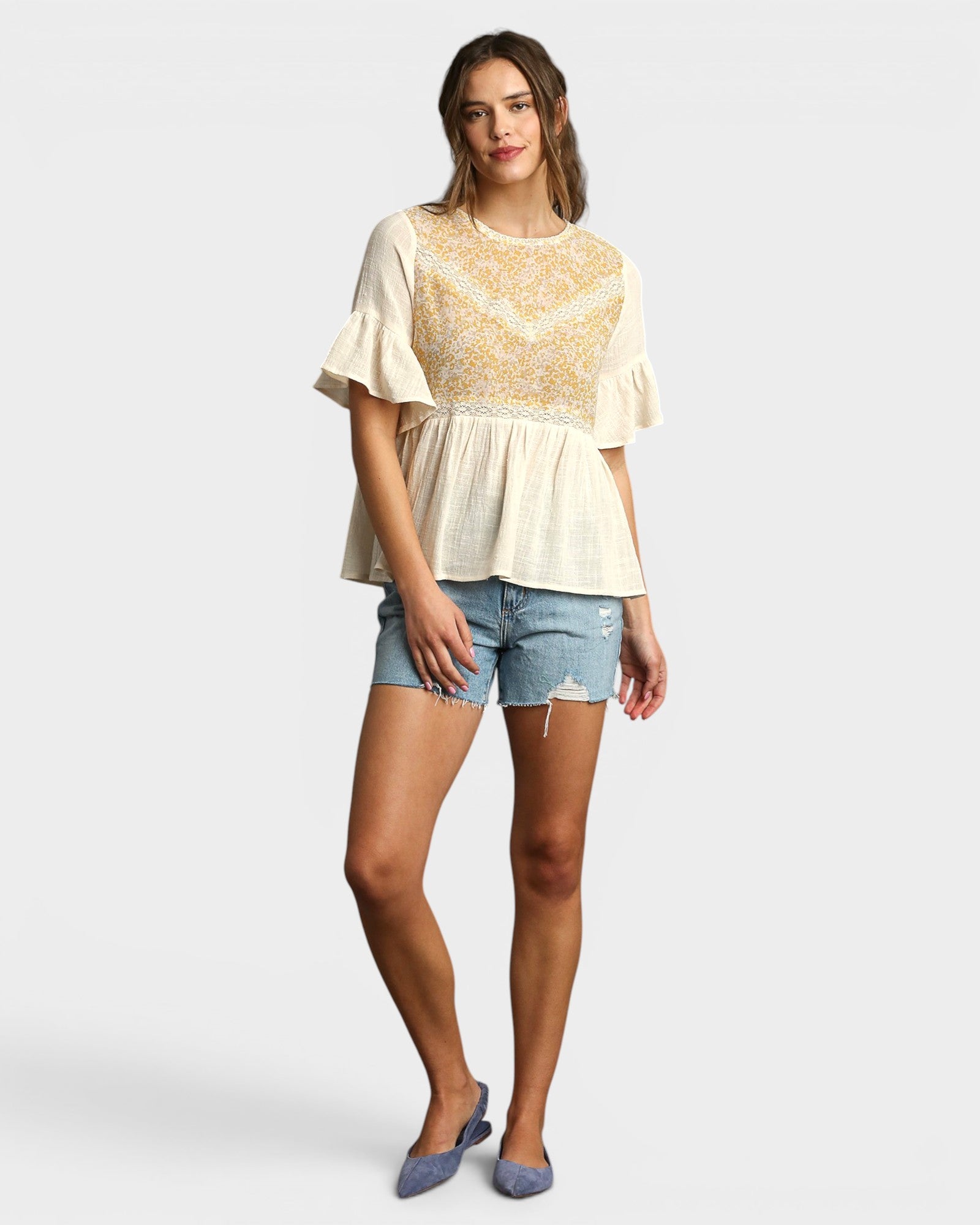 Woman wearing a lace top and denim shorts on a white background