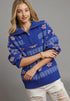 Woman wearing a blue patterned sweater with a gray background