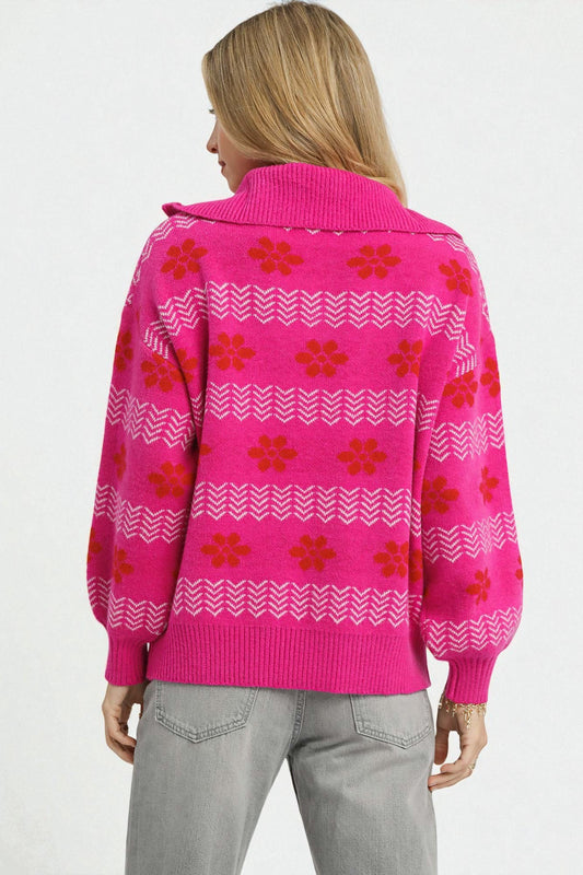 Person wearing a bright pink sweater with red floral patterns on a white background
