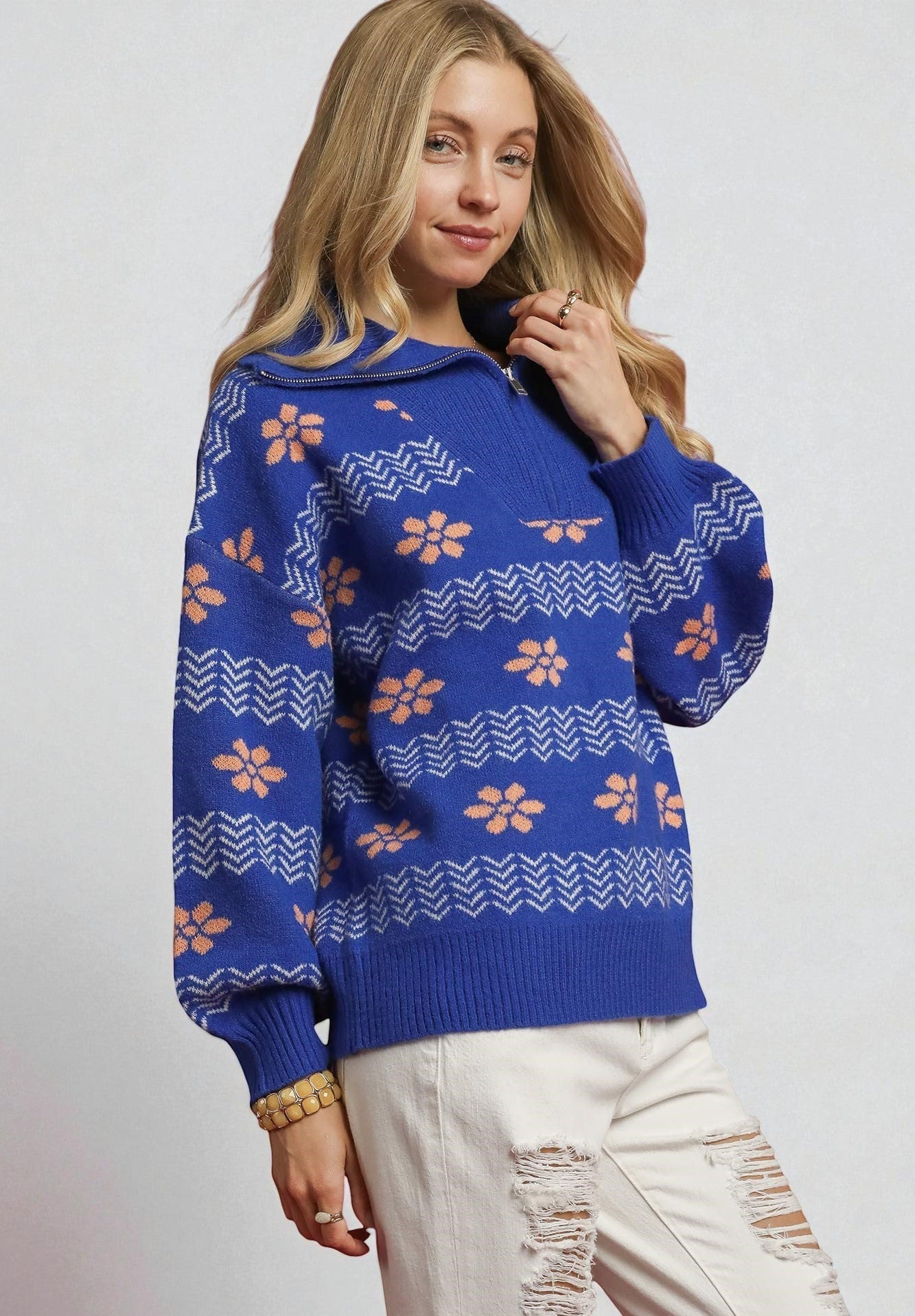 Woman wearing a blue sweater with floral pattern on a plain background