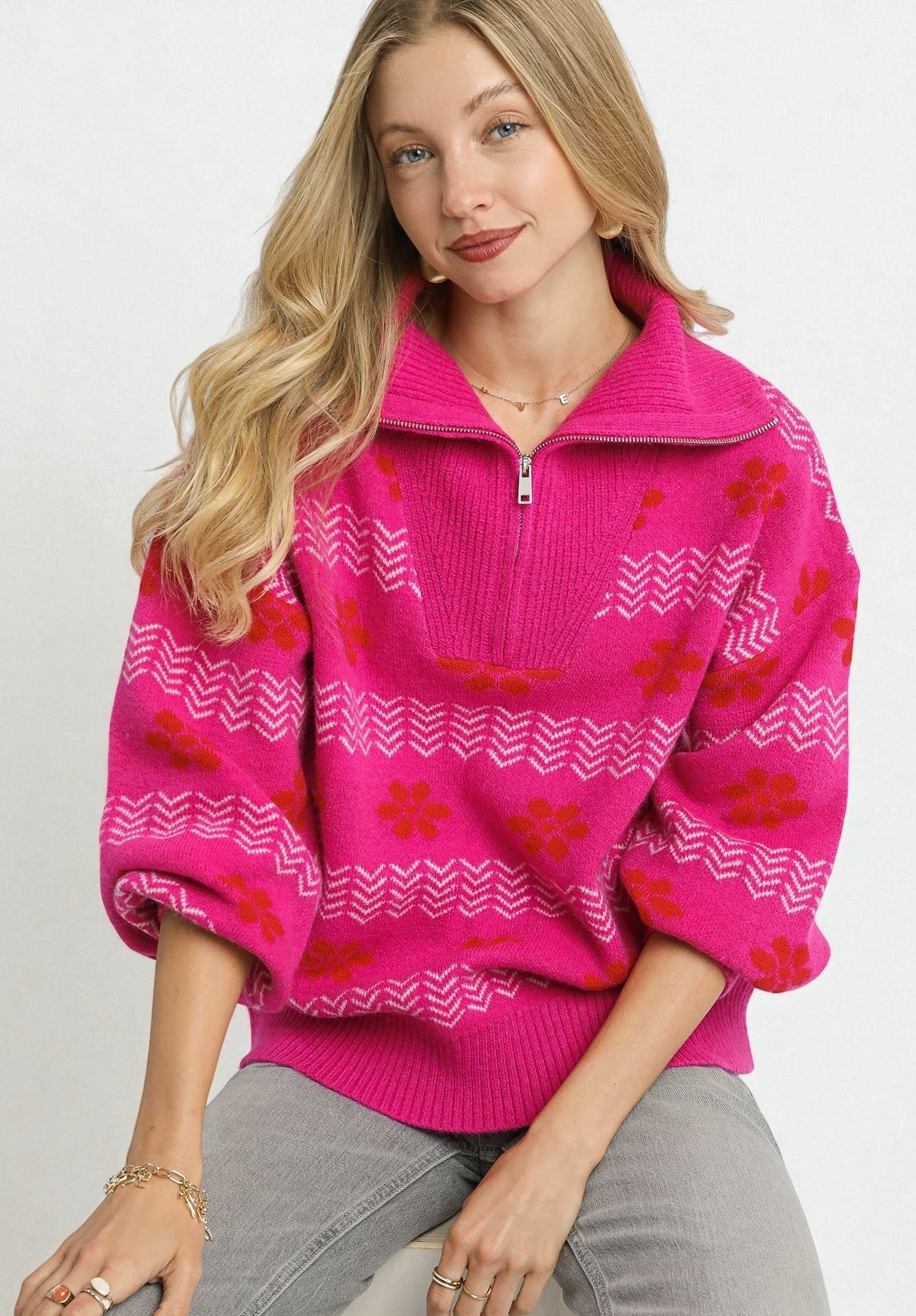 Woman wearing a pink sweater with red floral patterns on a white background