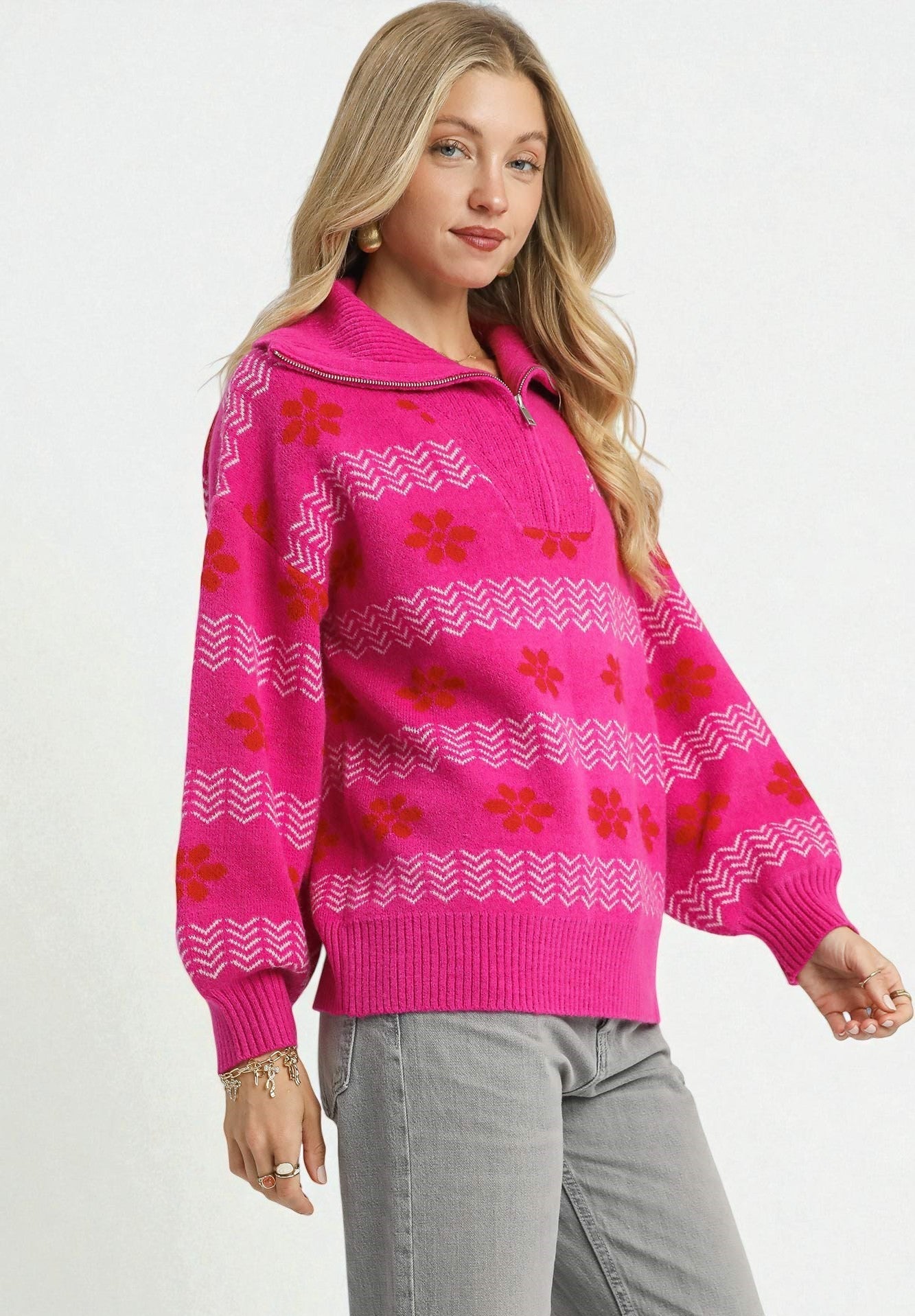 Woman wearing a bright pink sweater with red floral patterns on a white background