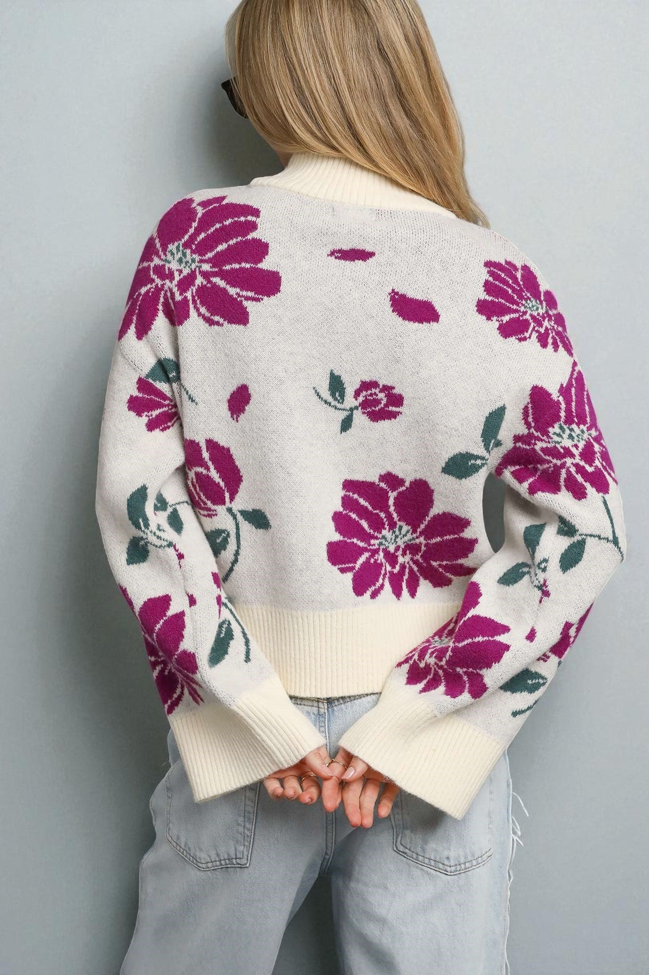 Person wearing a floral cardigan with pink flowers on a plain background