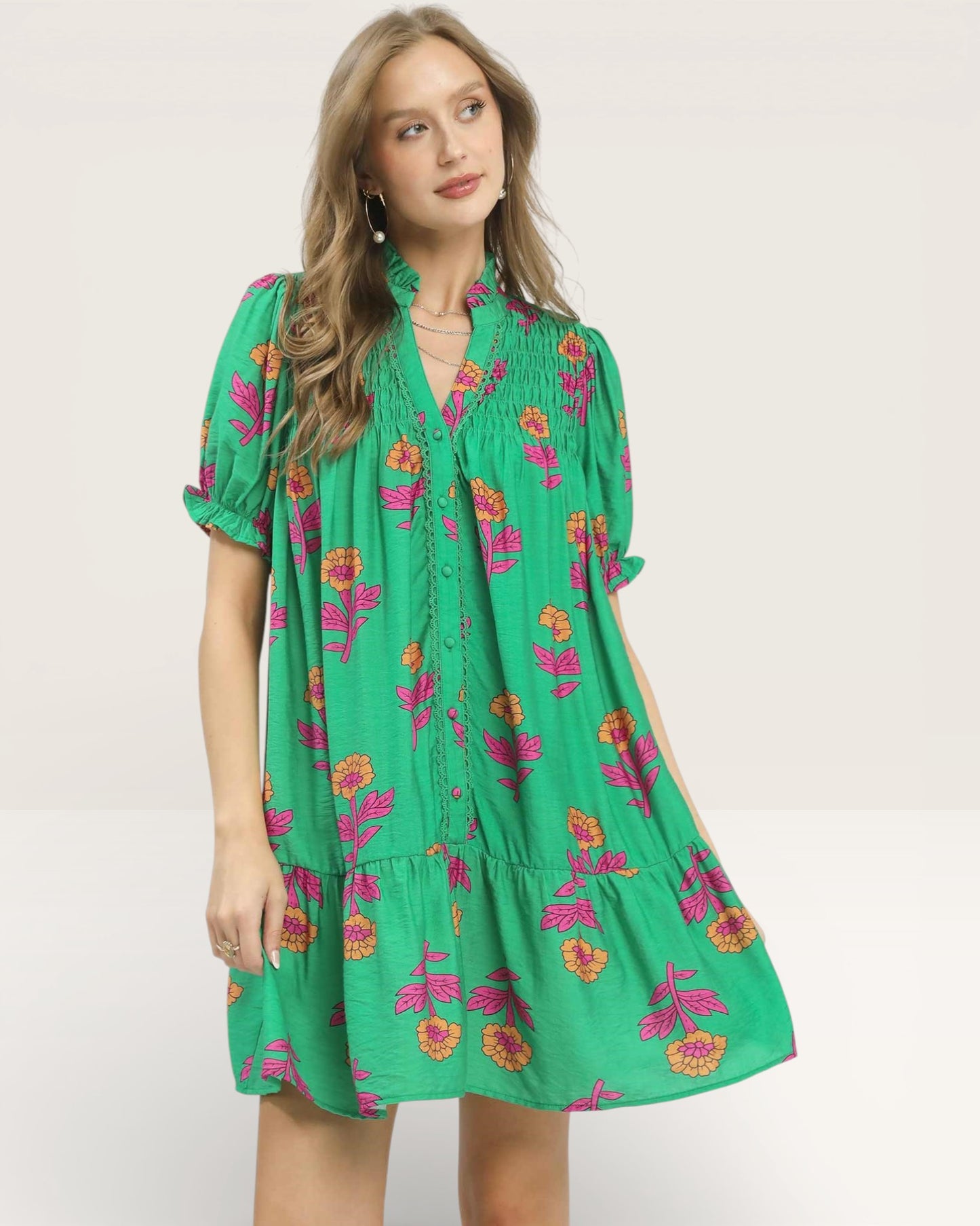Woman wearing a green floral dress on a plain background