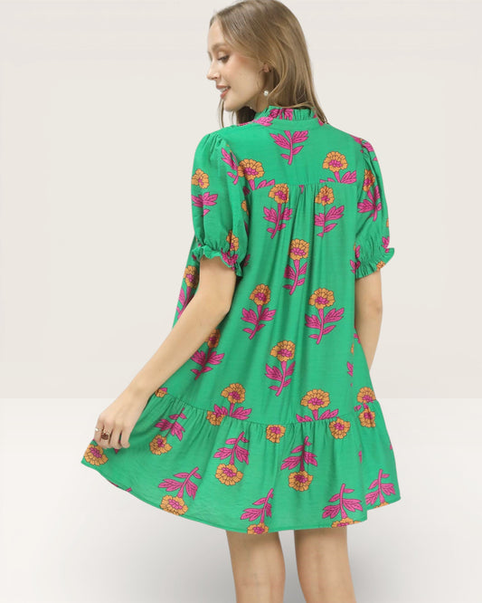 Woman wearing a green dress with floral pattern on a white background