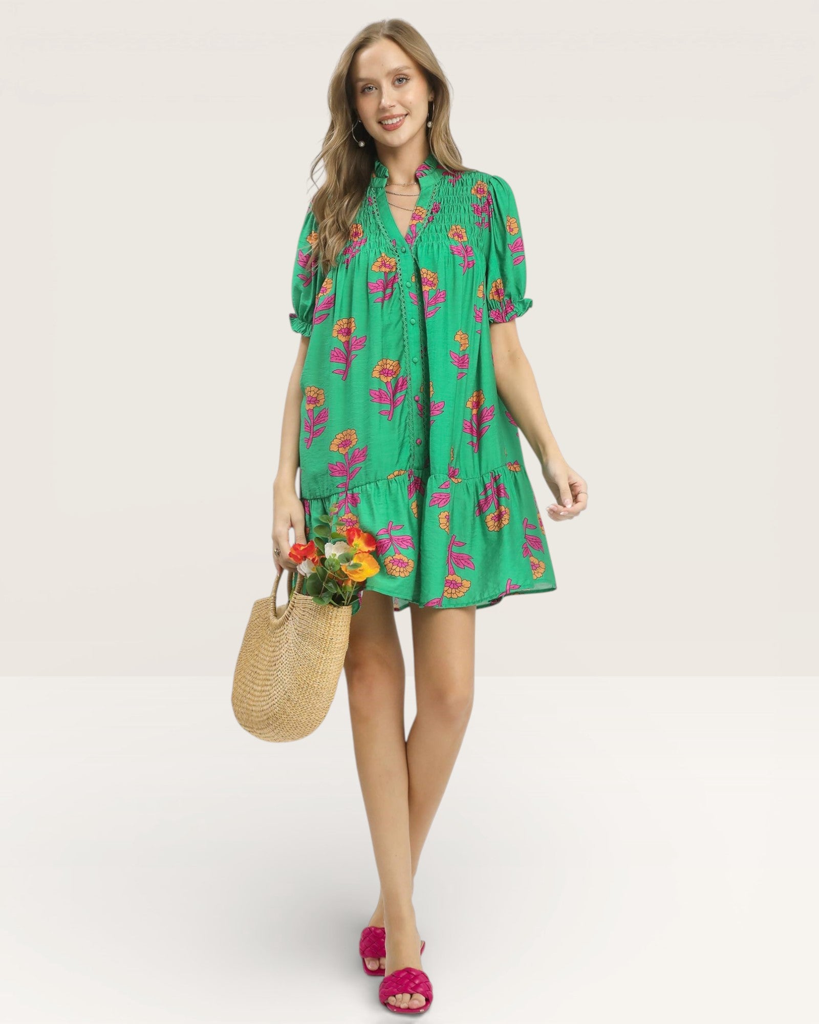 Woman wearing a green floral dress holding a straw bag on a white background