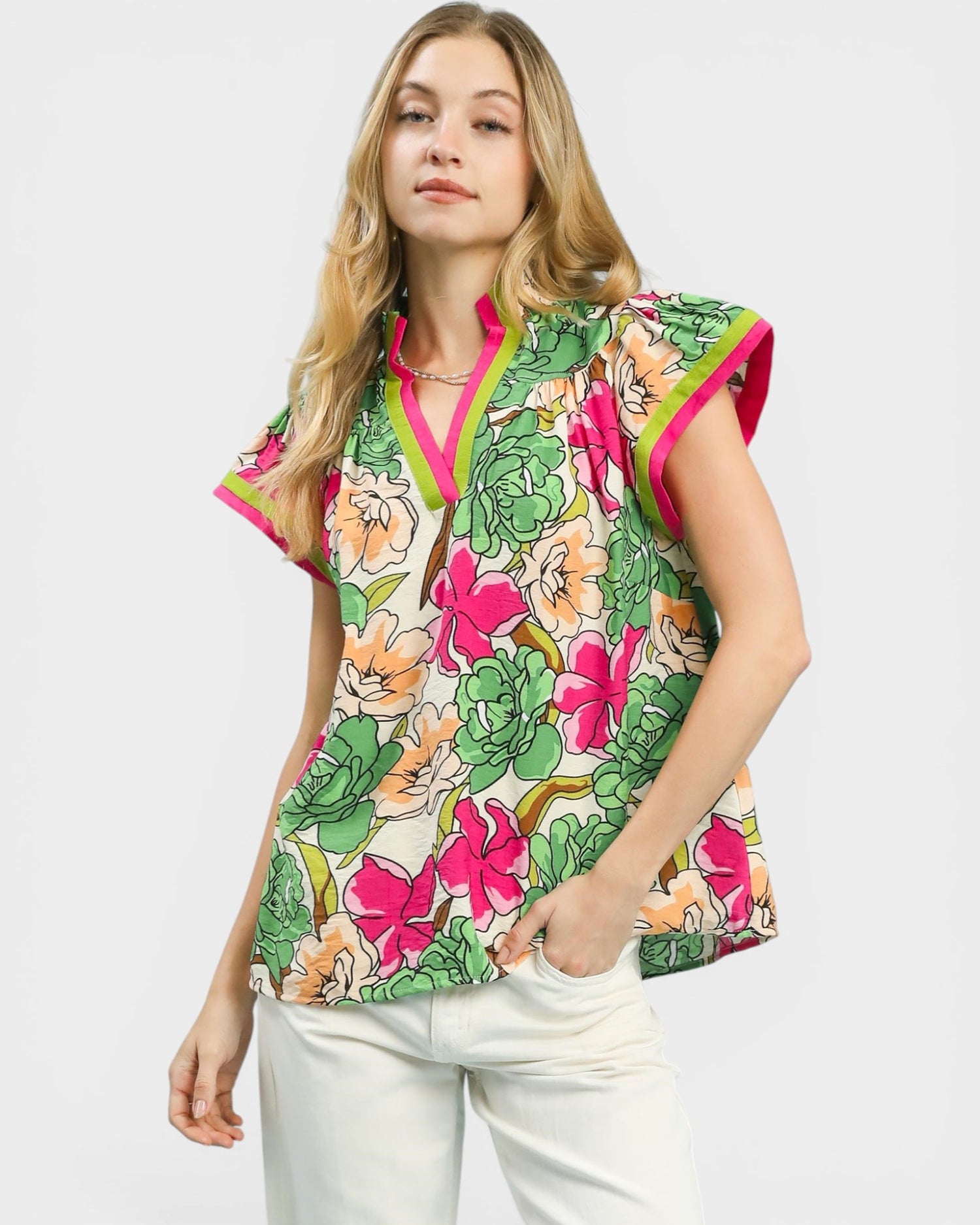 Woman wearing a colorful floral blouse with pink accents on a white background