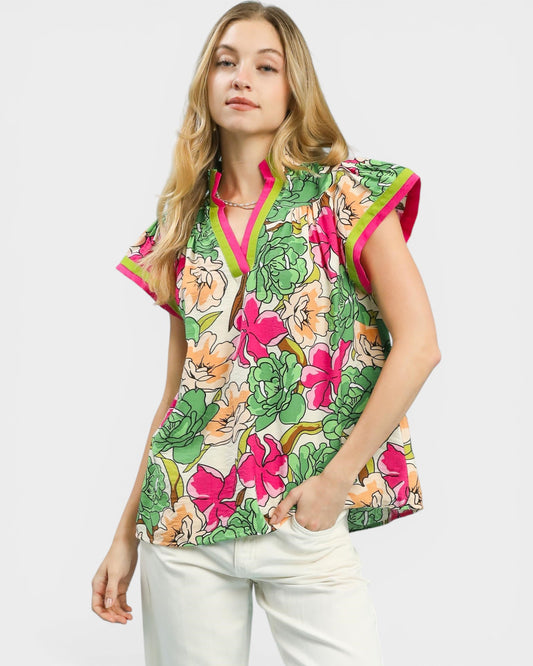 Woman wearing a colorful floral blouse with pink accents on a white background