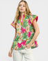 Woman wearing a colorful floral blouse with pink accents on a white background