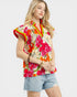 Woman wearing a colorful floral sleeveless top with denim shorts on a white background