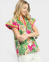 Woman wearing a colorful floral blouse with pink accents on a white background