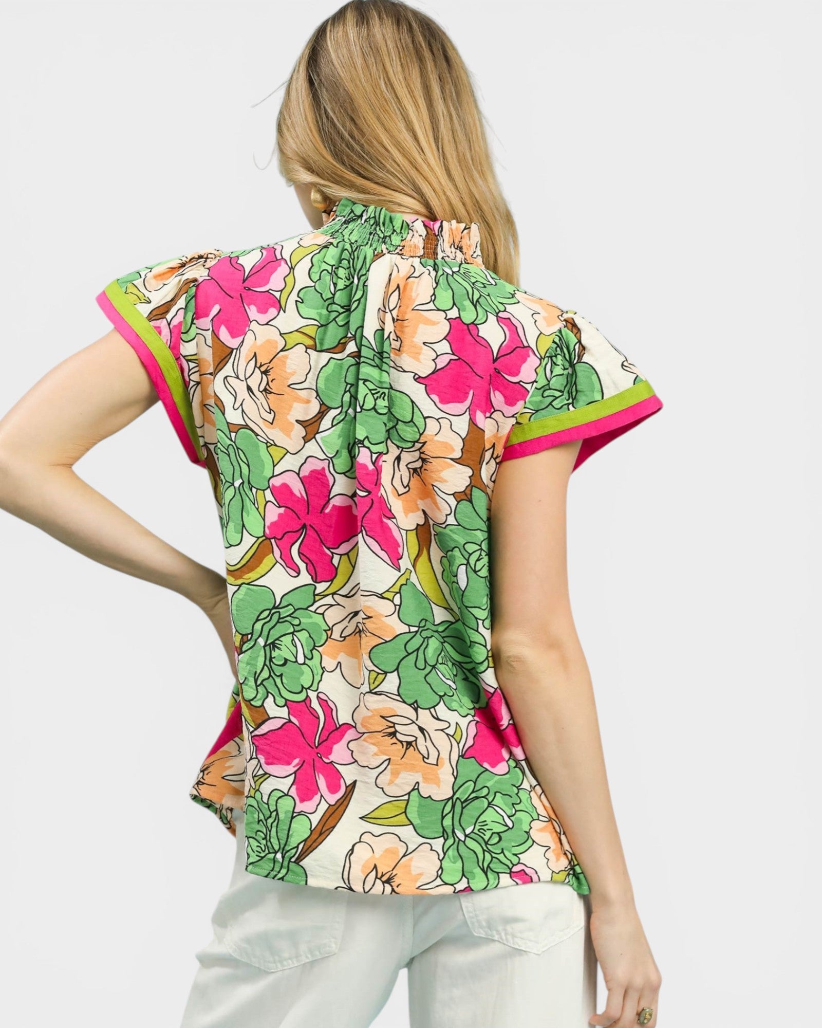 Woman wearing a colorful floral blouse with a plain background