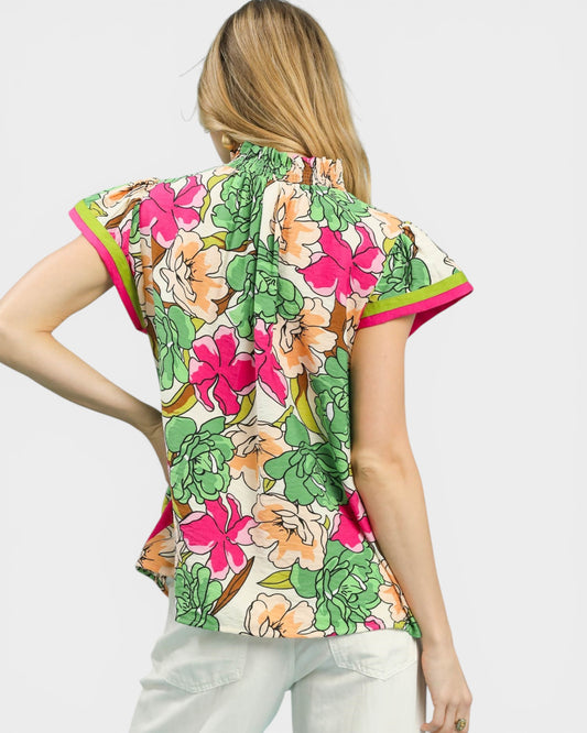 Woman wearing a colorful floral blouse with a plain background