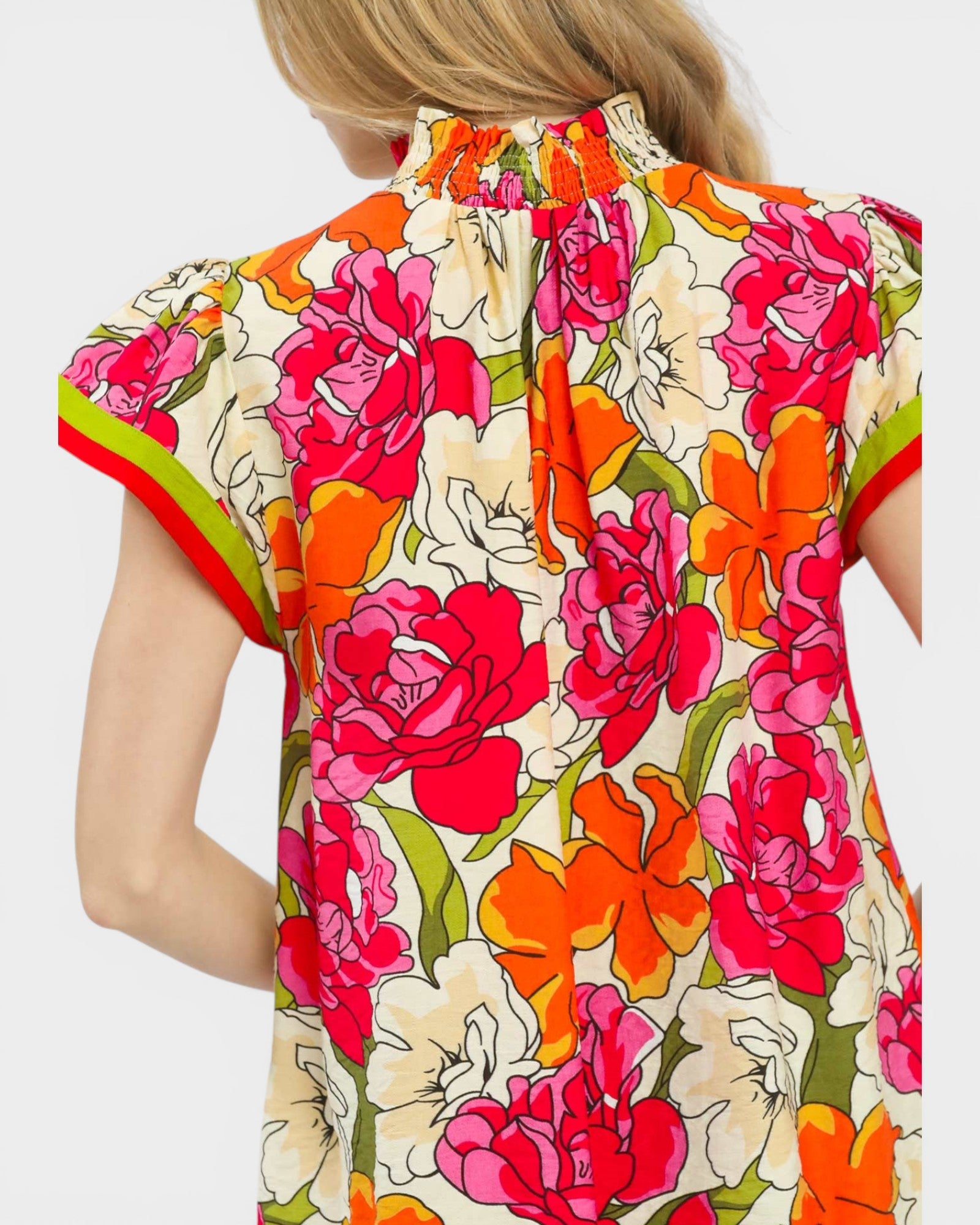 Woman wearing a colorful floral dress with a plain background