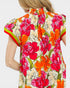 Woman wearing a colorful floral dress with a plain background