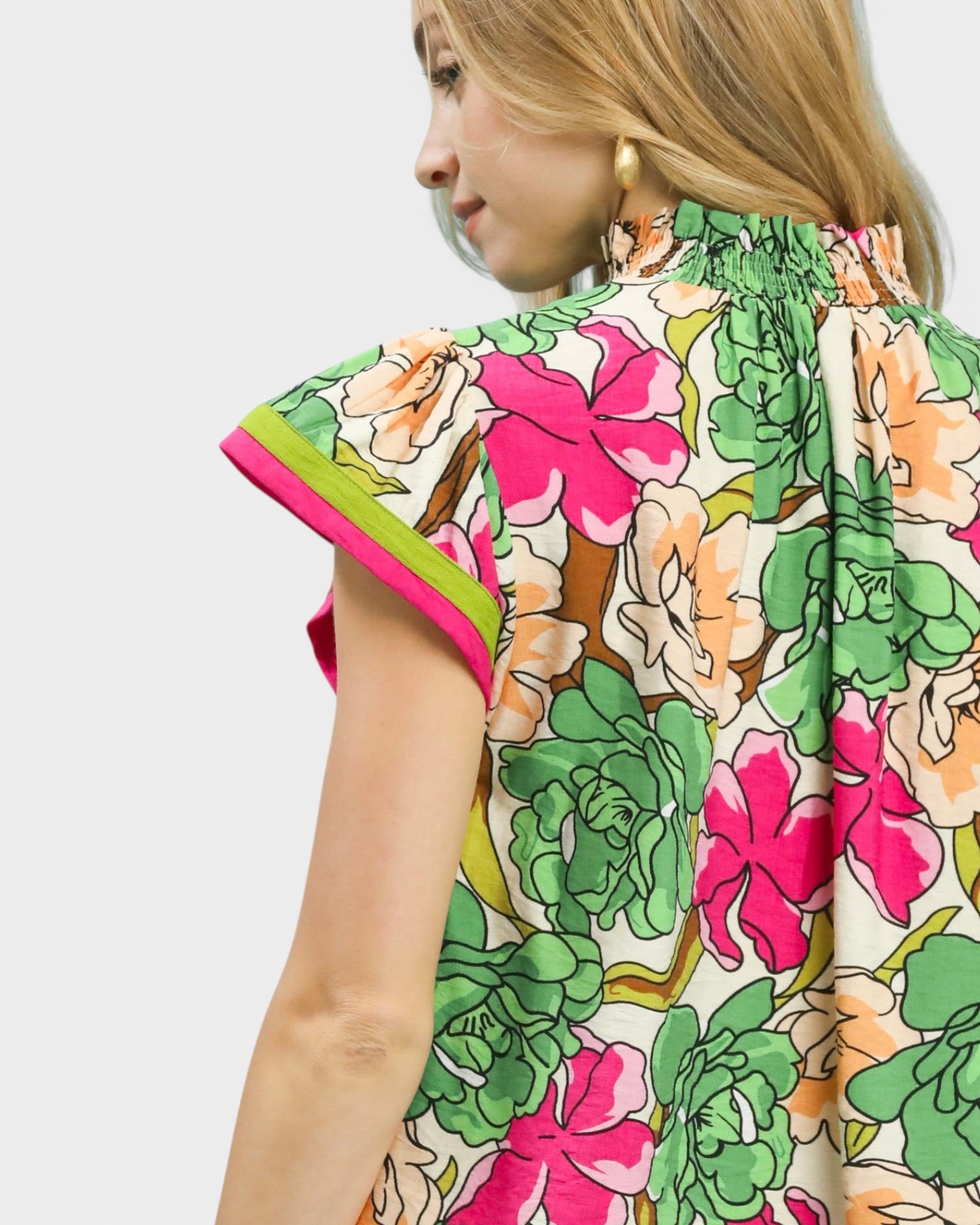 Woman wearing a colorful floral dress with a plain background
