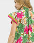 Woman wearing a colorful floral dress with a plain background