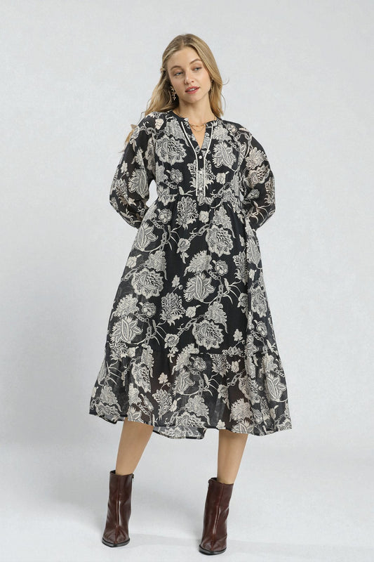 Woman wearing a black floral dress with brown boots on a white background