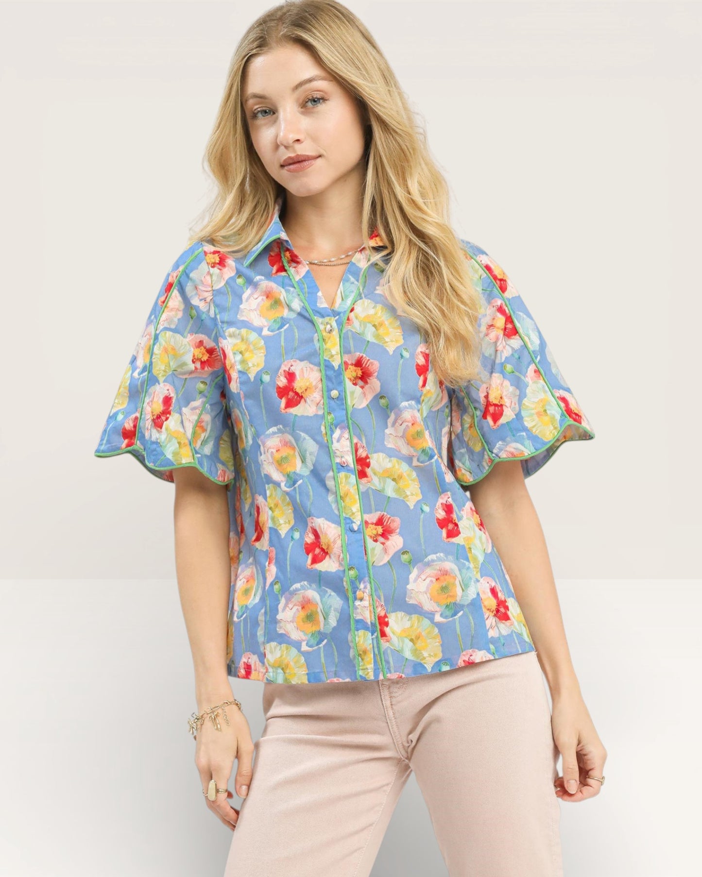 Woman wearing a colorful floral blouse with ruffled sleeves on a light background