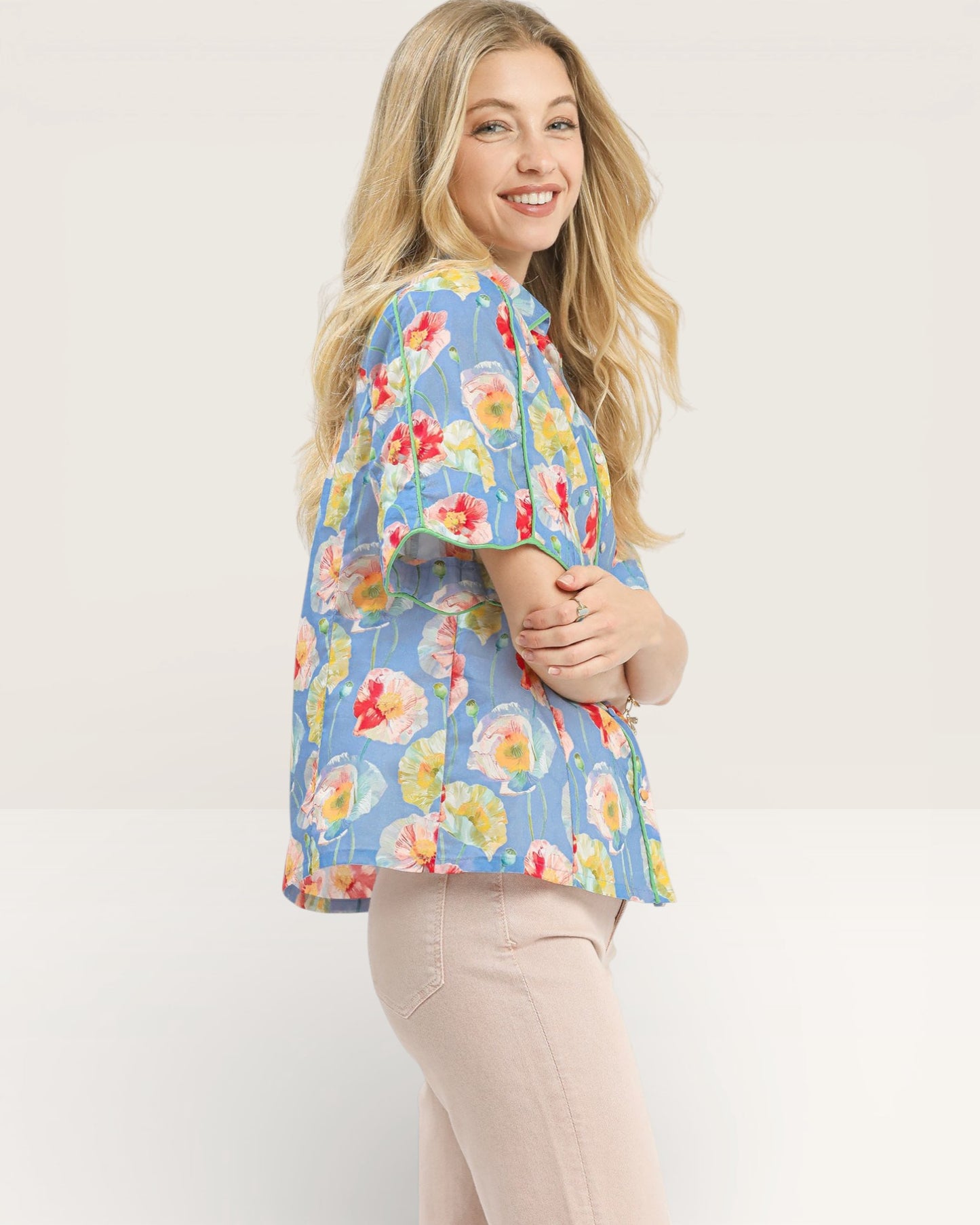 Woman wearing a colorful floral blouse against a white background