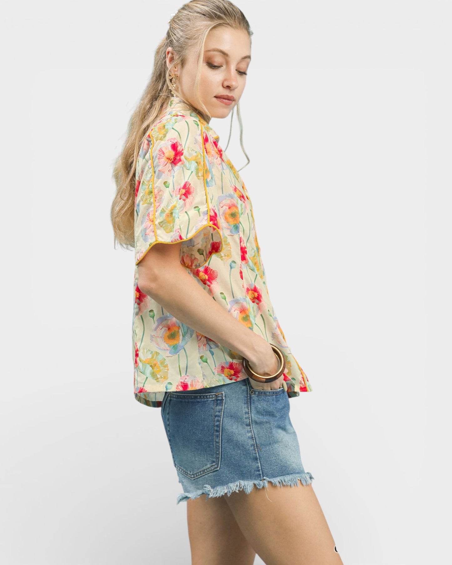 Woman wearing a floral blouse and denim shorts on a white background