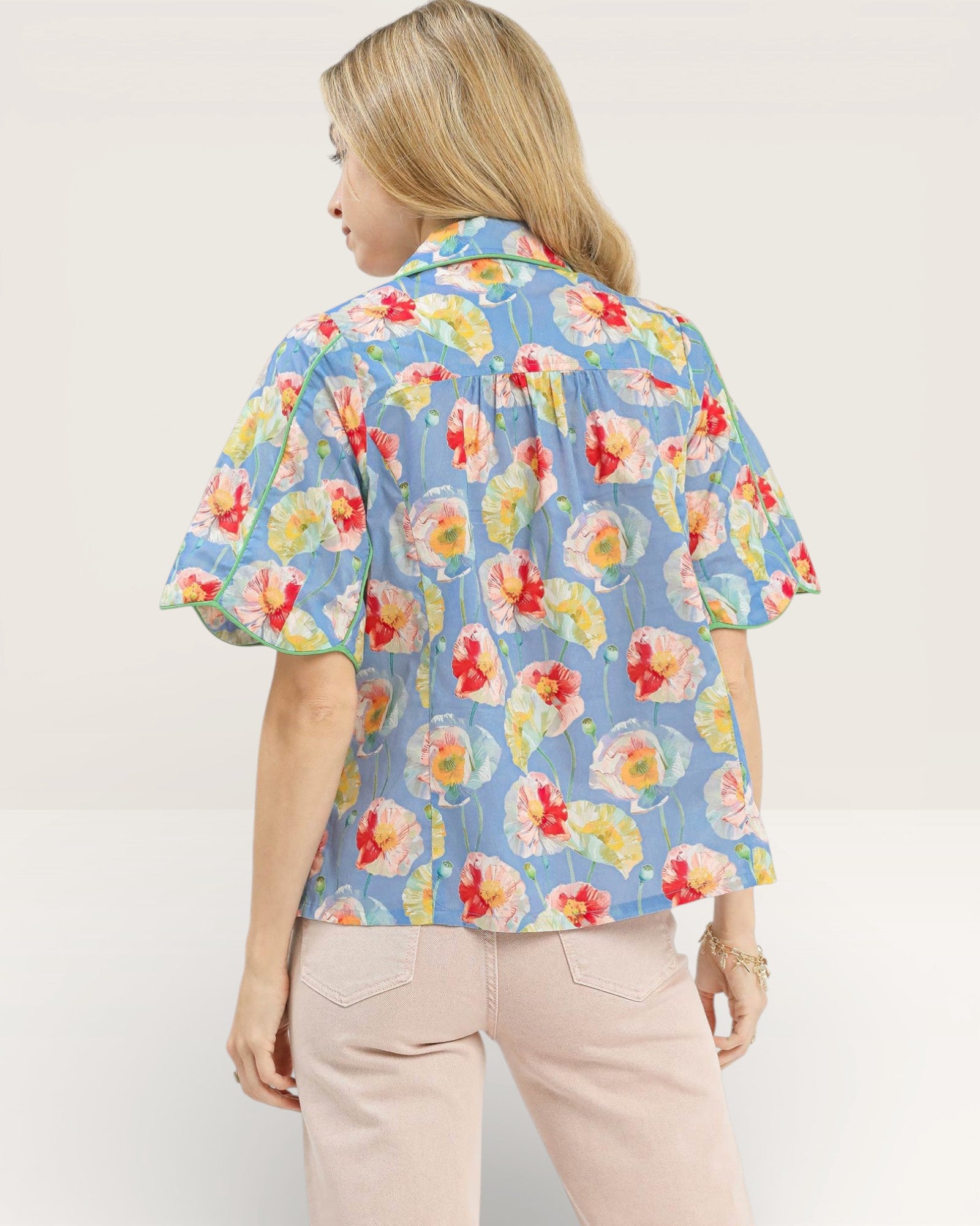 Woman wearing a colorful floral blouse with a plain background