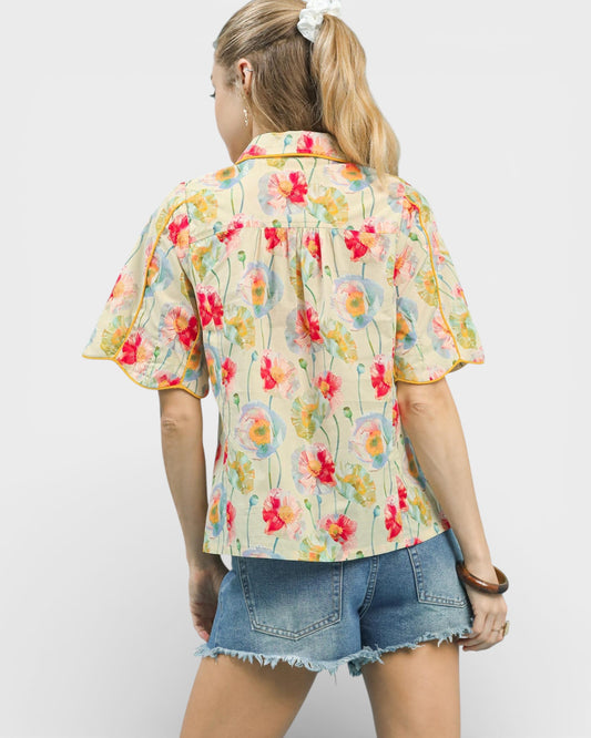 Woman wearing a colorful floral shirt and denim shorts on a white background