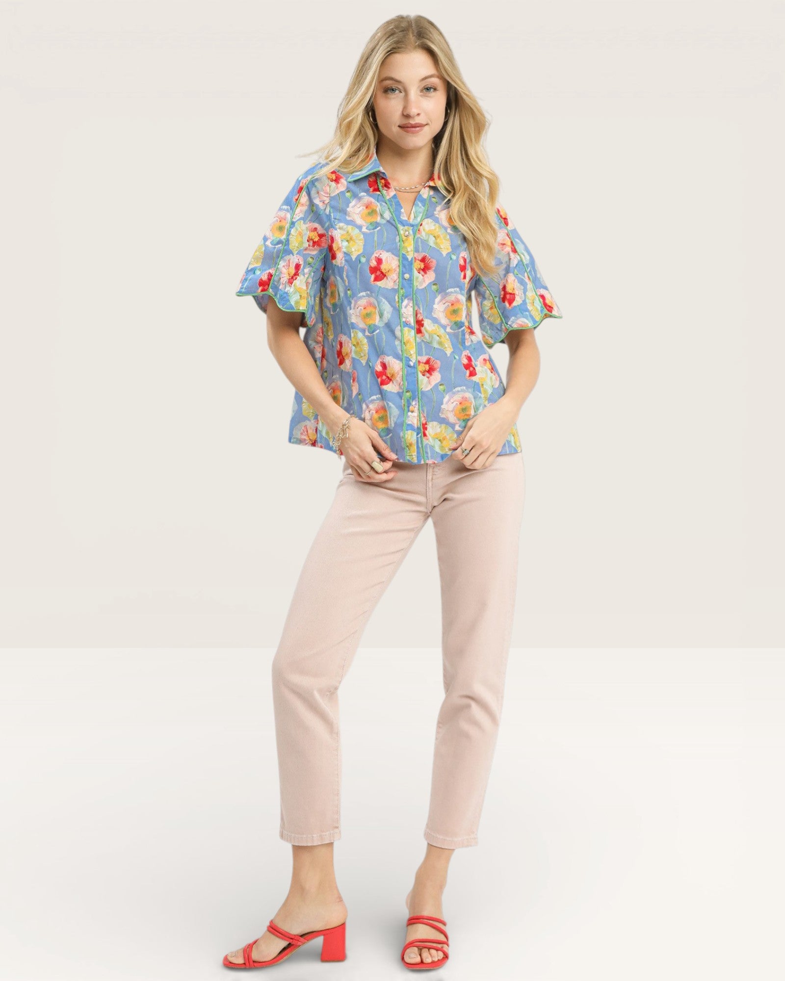 Woman wearing a floral blouse and pink pants on a white background