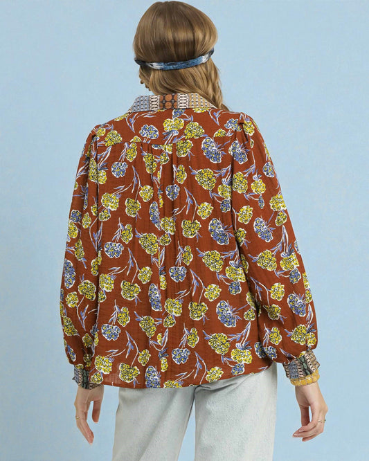 Person wearing a floral patterned shirt with a blue background