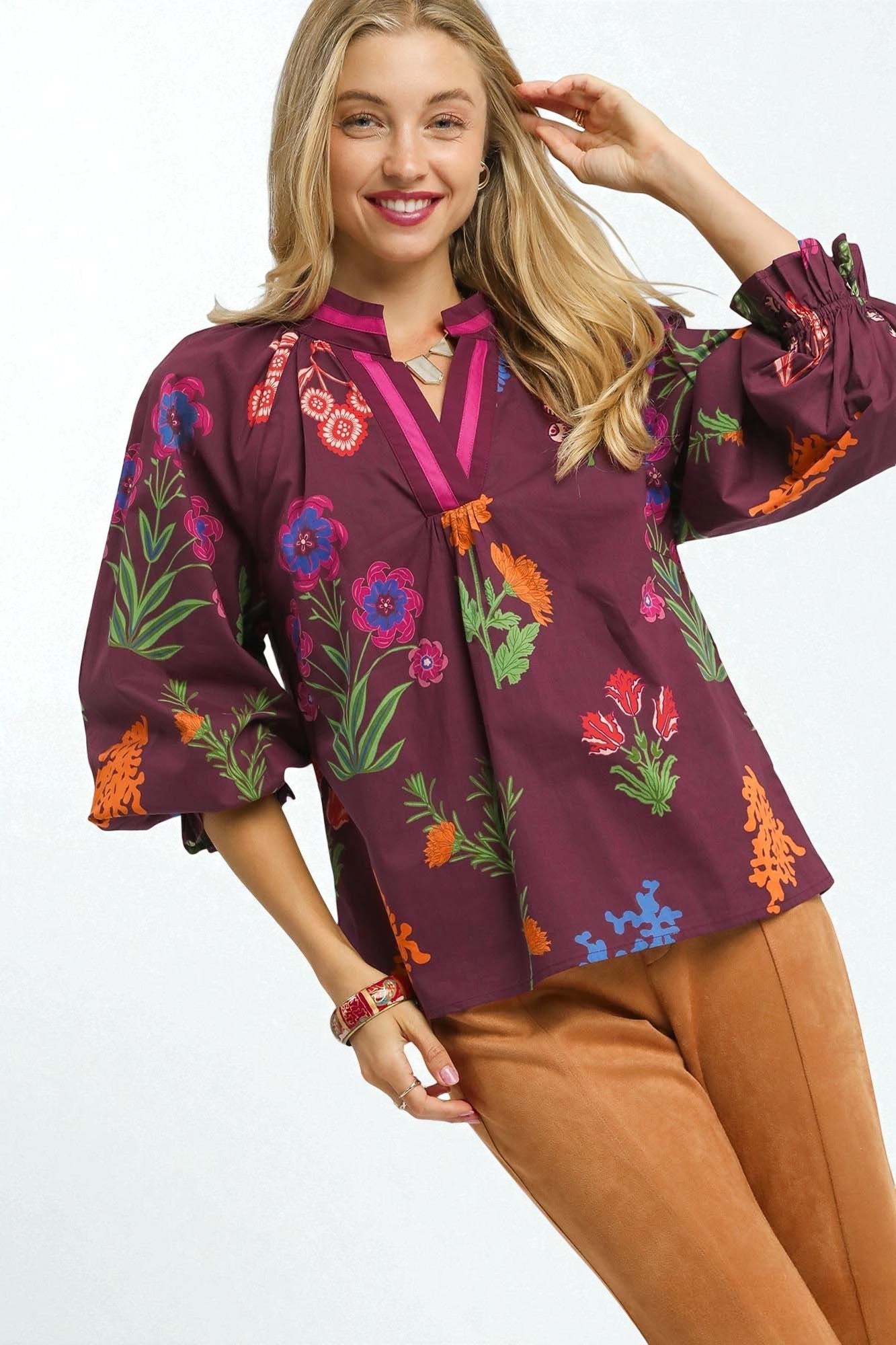 Woman wearing a colorful embroidered blouse with a plain background