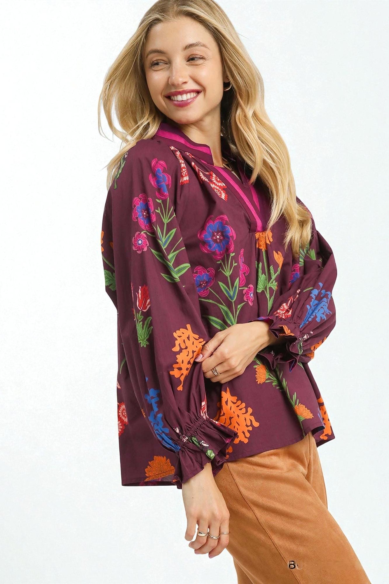 Woman wearing a purple blouse with colorful floral patterns on a white background