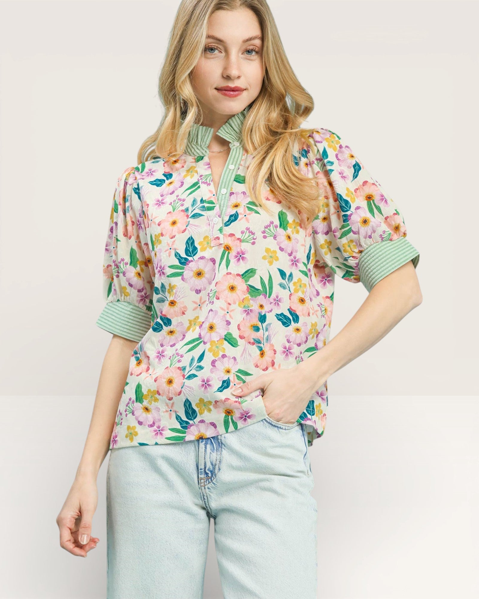 Woman wearing a floral blouse with green accents on a plain background