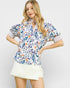 Woman wearing a floral blouse and white skirt on a plain background