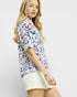 Woman wearing a colorful floral blouse against a plain background