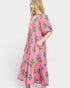Woman wearing a pink dress with floral patterns on a white background