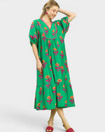 Woman wearing a green dress with floral patterns on a white background