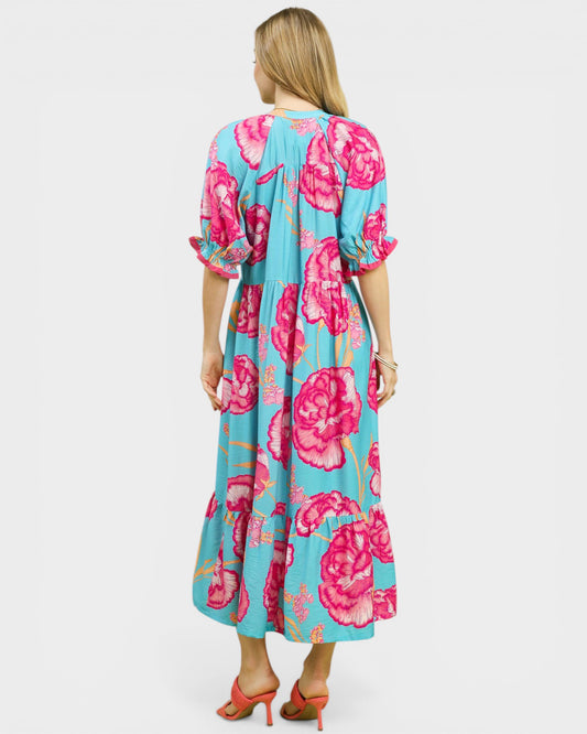 Woman wearing a floral dress with pink flowers on a light blue background