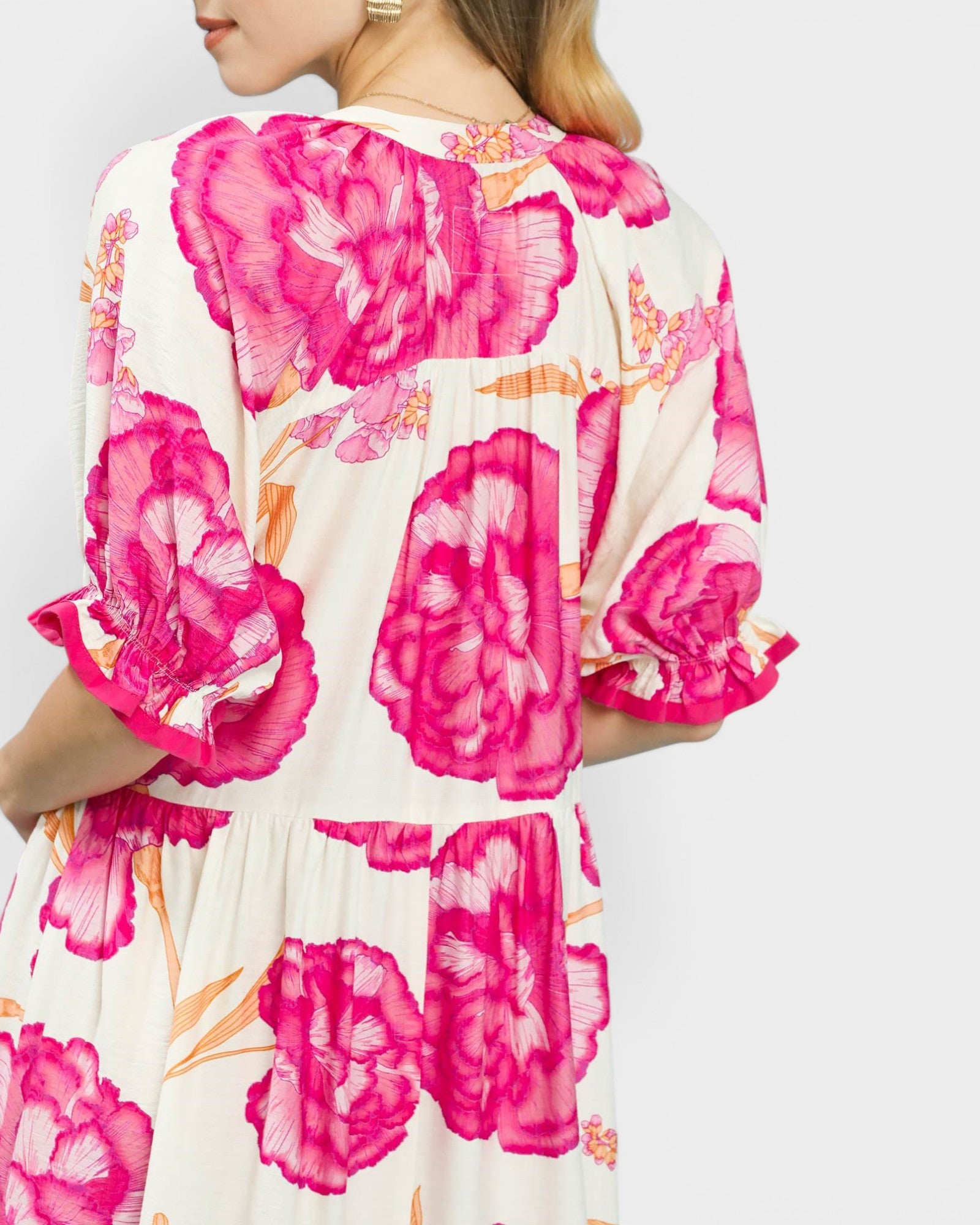 Woman wearing a dress with pink floral pattern on a white background
