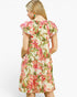 A woman shown from the back wearing a short-sleeve cream-colored dress with a vibrant pink and green floral print, set against a plain white background.