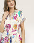 Woman wearing a colorful floral dress on a plain background