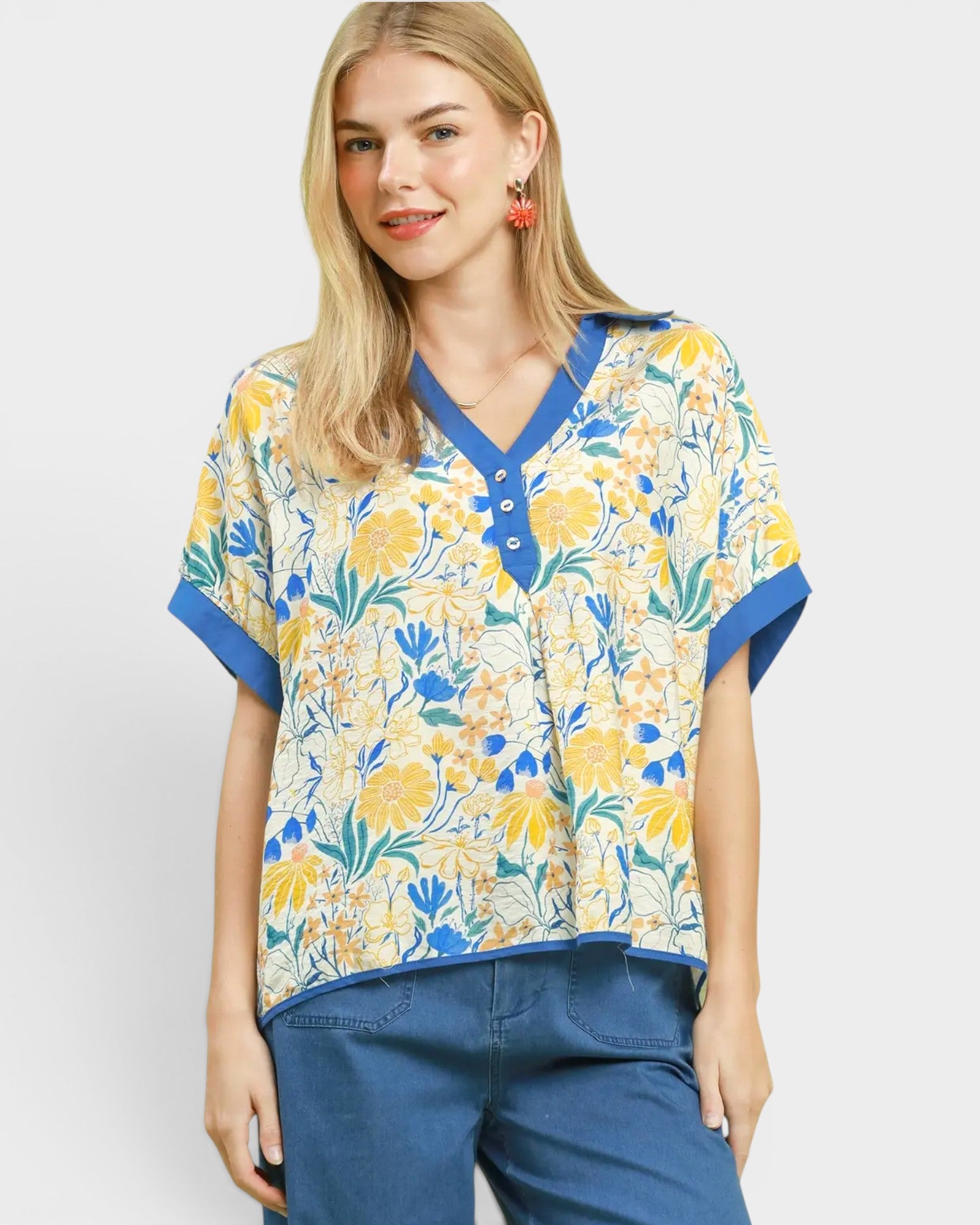 Woman wearing a colorful floral blouse with blue accents on a white background