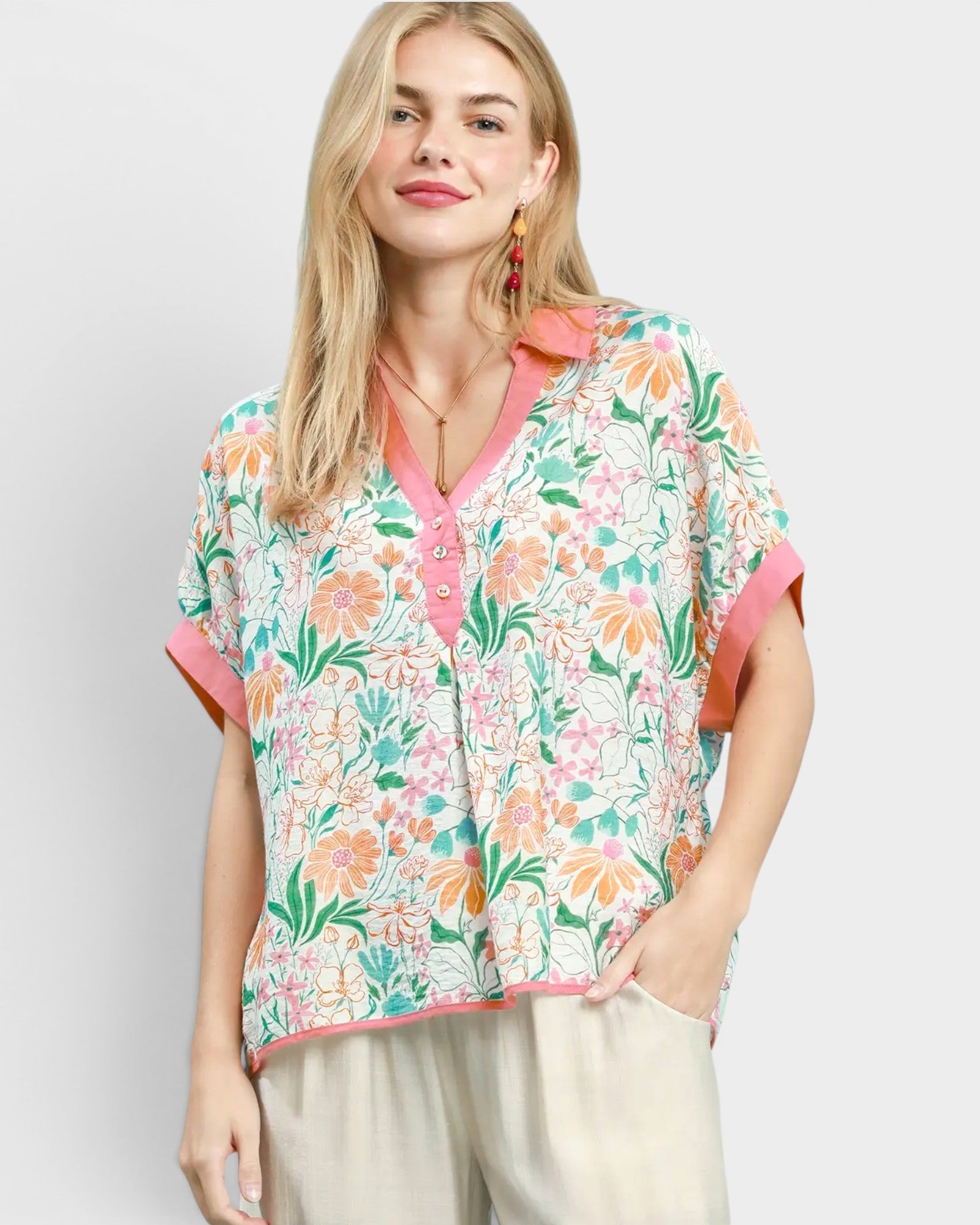 Woman wearing a floral blouse with pink accents on a plain background