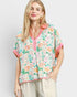 Woman wearing a floral blouse with pink accents on a plain background