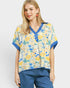 Woman wearing a colorful floral blouse with blue accents on a white background