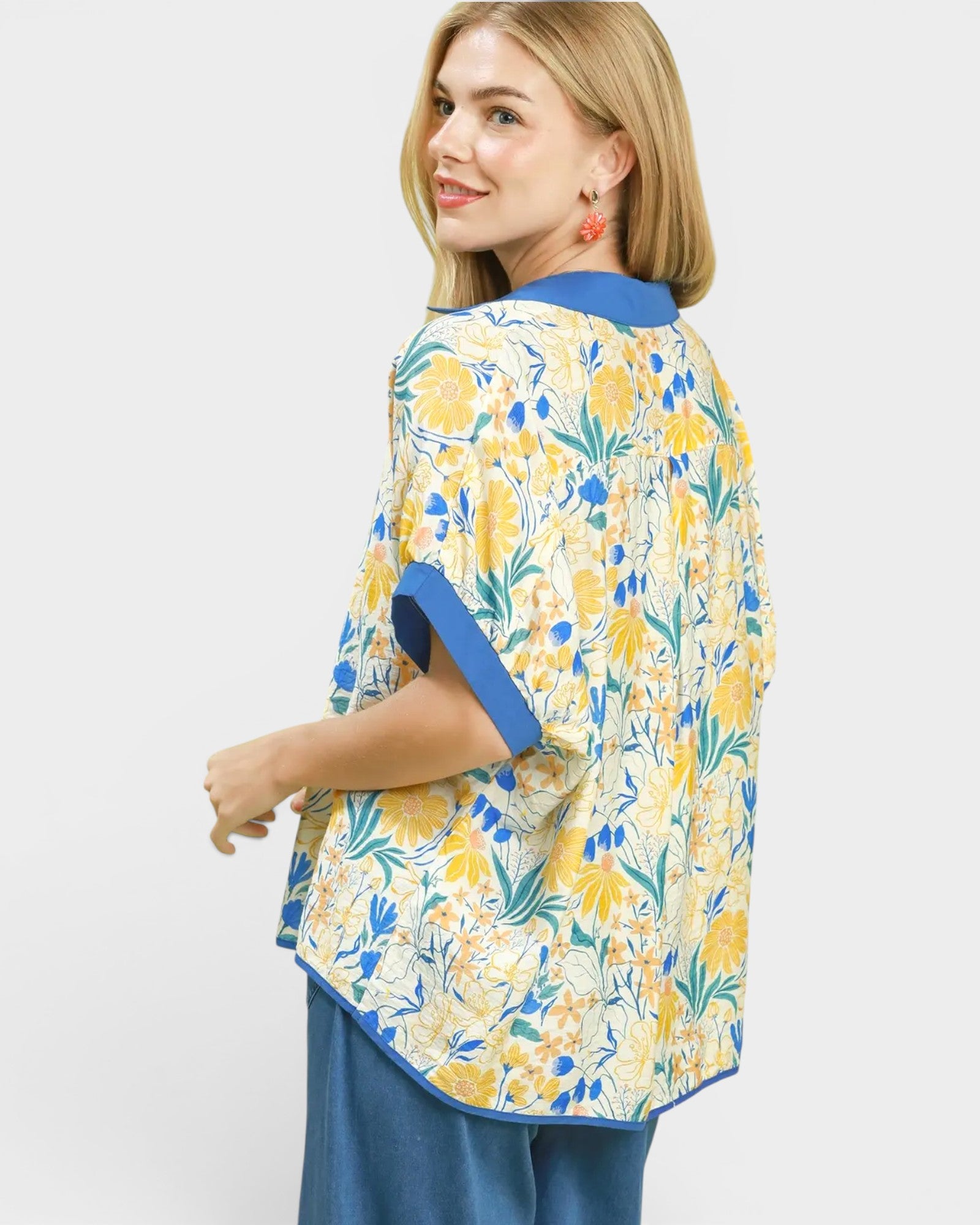 Woman wearing a yellow floral kimono-style garment with blue accents on a white background