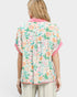 Woman wearing a floral blouse with pink trim on a white background