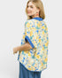 Woman wearing a yellow floral kimono-style garment with blue accents on a white background