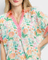 Woman wearing a floral blouse with pink accents on a plain background